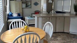 Una cocina compacta con armarios blancos, una mesa de comedor de madera y una pequeña isla.