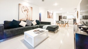 A modern living room with a grey sofa, white coffee table, and artwork on the walls. - Incredible- Fully funrished & equipped+ pool view - 1 block from 5th (Playa del Carmen)