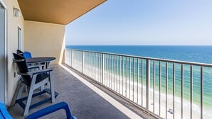 Ein Balkon mit Blick auf den Ozean, einem Tisch und blauen Stühlen.