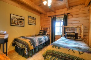 A cabin-style room with two beds, wooden walls, and a ceiling fan. - 3BR log cabin, Hot Tub, sleeps 9, exceptional view + free railroad tix (Bryson City)