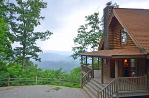 A wooden cabin with a porch and a view of mountains. - 3BR log cabin, Hot Tub, sleeps 9, exceptional view + free railroad tix (Bryson City)