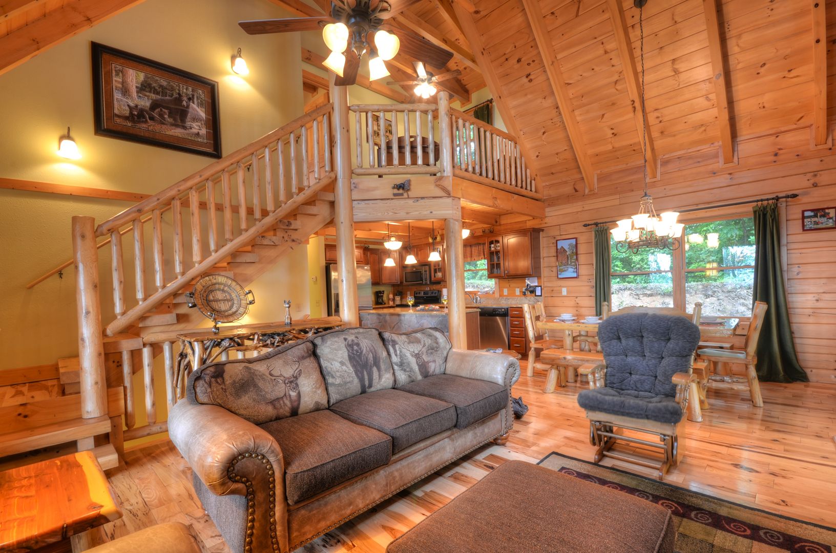 A log cabin interior with a wooden staircase, a sofa, a chair, and a dining area.
