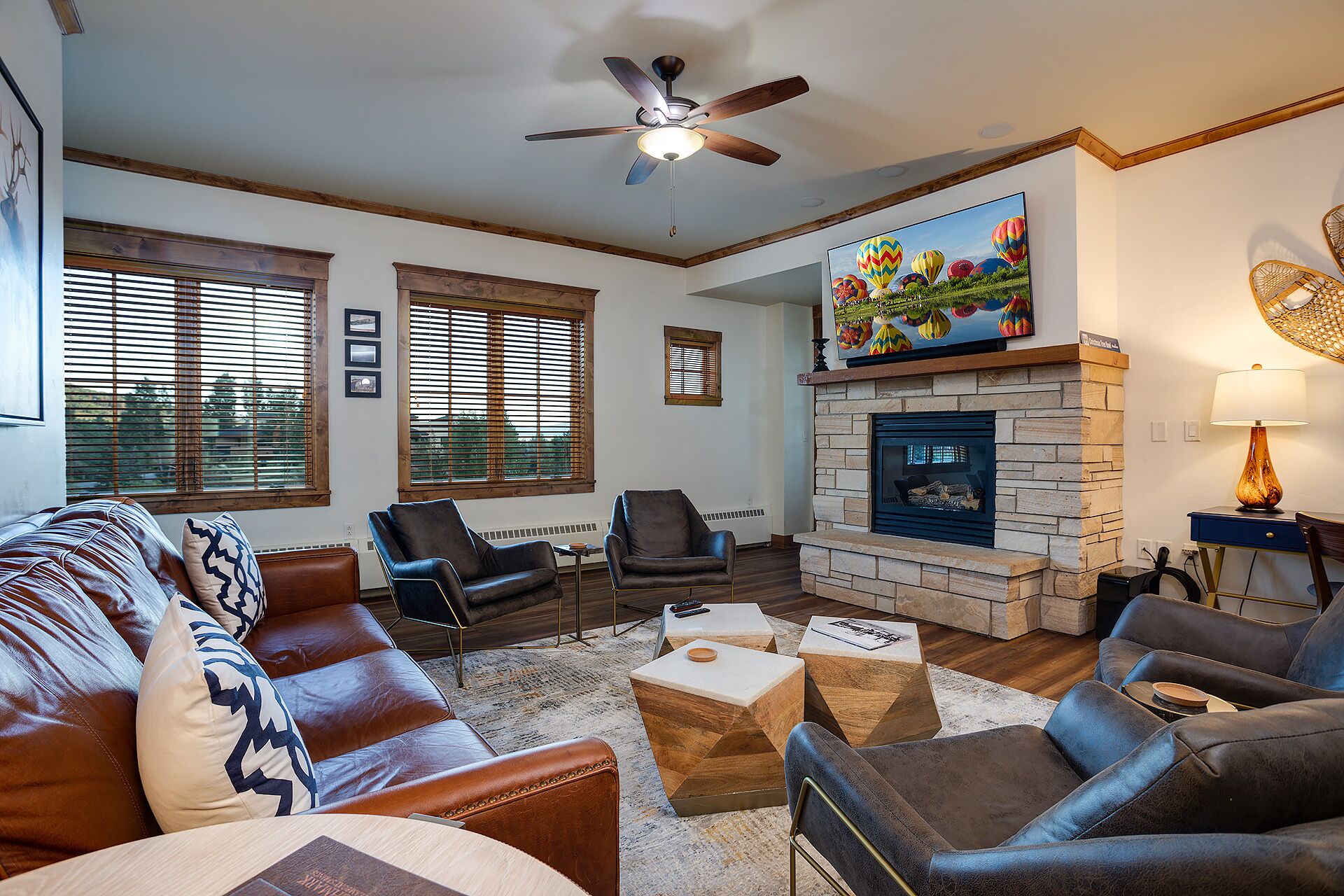 A living room with a fireplace, leather sofas, and a television mounted above it.
