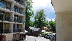 Un edificio de varios pisos con balcones, un letrero de Coca-Cola y un estacionamiento con plantas en macetas.