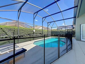 A covered outdoor swimming pool with a view of a residential area and hills in the background.