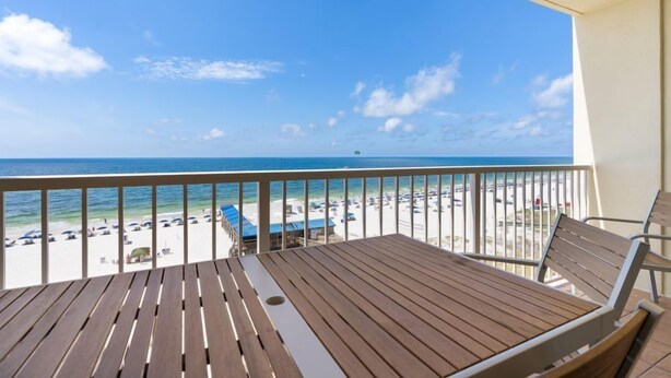 Eine Holzterrasse mit Blick auf Strand und Meer.