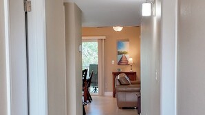 A hallway with a tiled floor, a dining area with chairs and a table, and a lamp. - Taste Of Paradise (Sanibel)