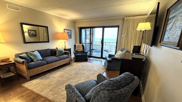 A living room with a sofa, armchairs, a coffee table, a TV, and a balcony with a view. - Cozy, yet spacious 2 bedroom oceanfront condo with free WiFi and a stunning view of the ocean located midtown just a few steps to the beach! (Ocean City)