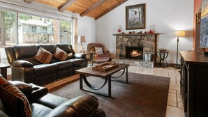 Una sala de estar acogedora con chimenea de piedra, sofás de cuero y techo de madera.
