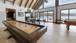 Amplia habitación con mesa de fútbol de mesa, mesa de billar y vista a un lago a través de amplias ventanas.