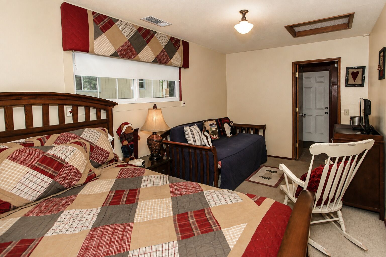 A bedroom with a bed, a chair, a desk, a lamp, a window, and a door.