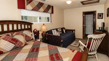 A bedroom with a bed, a chair, a desk, a lamp, a window, and a door.
