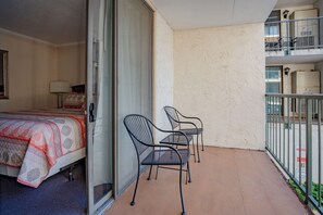 Un balcón con una cama, dos sillas y una mesa.