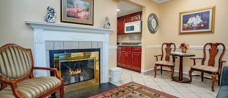 Una sala de estar con chimenea, un comedor con mesa y sillas, y una cocina con armarios de madera.