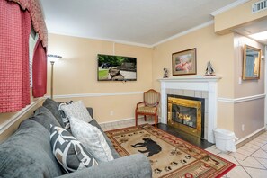 Ein Wohnzimmer mit Kamin, einer Couch, einem Teppich und einem Gemälde an der Wand.