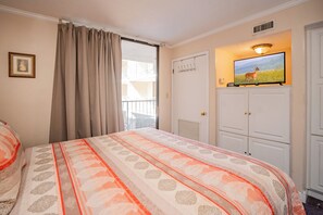 Ein Hotelzimmer mit einem Bett, einem an der Wand befestigten Fernseher und einem Fenster mit Vorhängen.