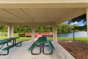 A covered picnic area with picnic tables and a view of a lake.