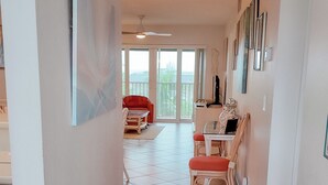 A hallway with a patterned rug, a dining area with a table and chairs, and a view of the outdoors through large windows. - Top Floor View With Bottom Floor Pricing...... (Sanibel)