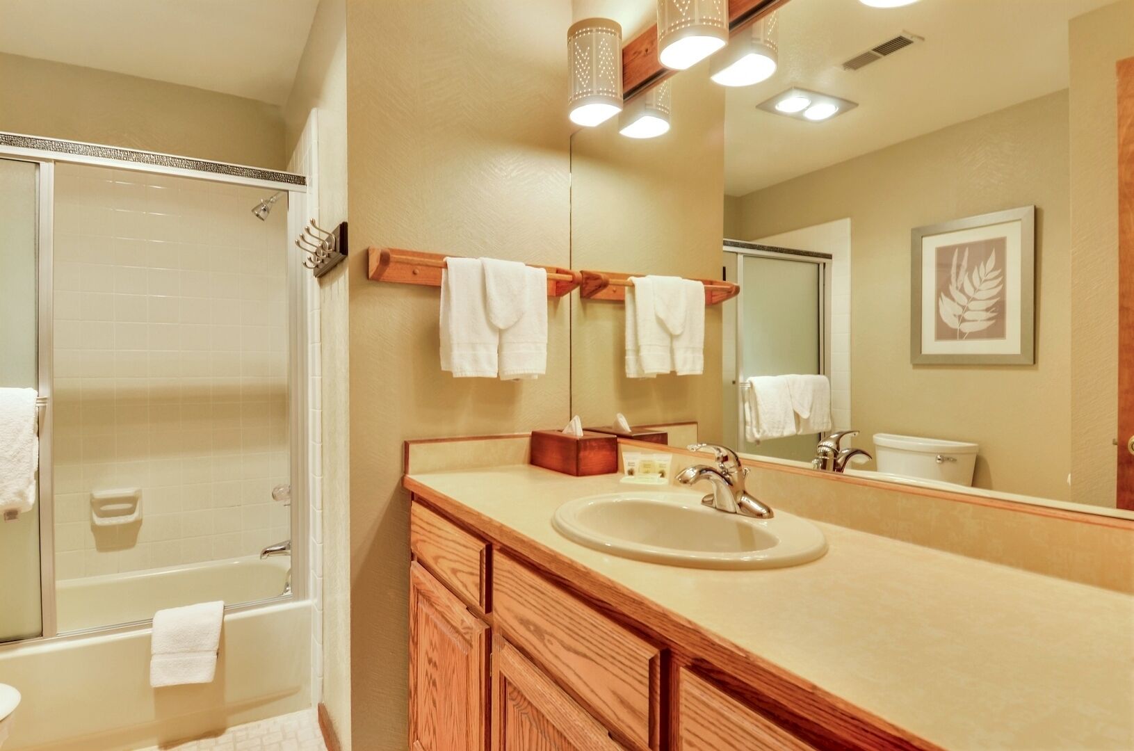 A bathroom with a glass-enclosed shower, a wooden vanity with a sink, and a large mirror.