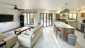 Een moderne keuken met een groot eiland, barstoelen en een eettafel.