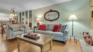 A living room with a sofa, two armchairs, a coffee table, a chandelier, a mirror, and a lamp. - two bedroom condo sleeps 4 persons (Gatlinburg)