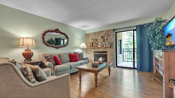 A living room with a fireplace, a sofa, a coffee table, and a television. - two bedroom condo sleeps 4 persons (Gatlinburg)