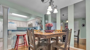 A kitchen with white cabinets, a wooden dining table, and a red stool. - two bedroom condo sleeps 4 persons (Gatlinburg)
