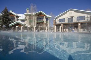 Un hôtel doté d’une grande piscine qui reflète les bâtiments et les arbres.