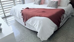A modern bedroom with a large bed, a bedside table, a lamp, and a view through the window. - Trendy 2BED *Wi-fi High Speed-Private Jacuzzi-Steps the ocean (Playa del Carmen)