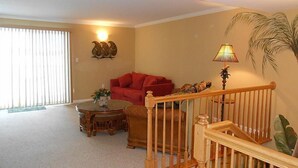 Ein Wohnzimmer mit einem roten Sofa, einem runden Couchtisch und einer Treppe mit Holzwangen.