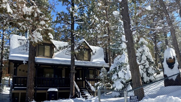 Un chalet avec une façade en bois, de nombreuses fenêtres et une véranda couverte.