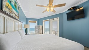 Ein Schlafzimmer mit einem großen Bett, einem Deckenventilator, einem Fernseher und Meerblick.