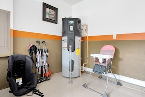 A corner of a room with a water heater, crutches, a baby walker, and a black suitcase. - Champions Gate Pool Home | 3 King Suites | Game Room | Dog Friendly (Champions Gate)
