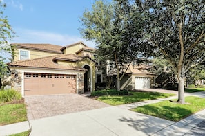 A residential property with a garage, driveway, and well-maintained lawn. - Champions Gate Pool Home | 3 King Suites | Game Room | Dog Friendly (Davenport)