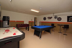 A recreational room with a pool table, foosball table, and a dartboard.