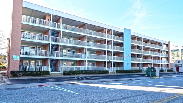 Un motel à plusieurs étages, doté de balcons, d’un escalier central et d’un parking.