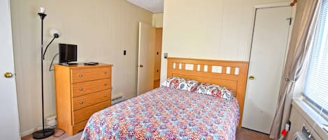 A bedroom with a bed, dresser, lamp, and radiator.