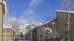 A snow-covered street with multi-story buildings, some with balconies. - SHB39 | Nice Mtn Condo | Hot Tub | On Free City Bus Route (Steamboat Springs)