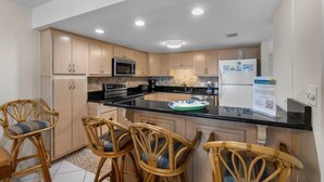 Una cucina moderna con mobili in legno, un piano di lavoro nero e un'isola centrale con sgabelli da bar.