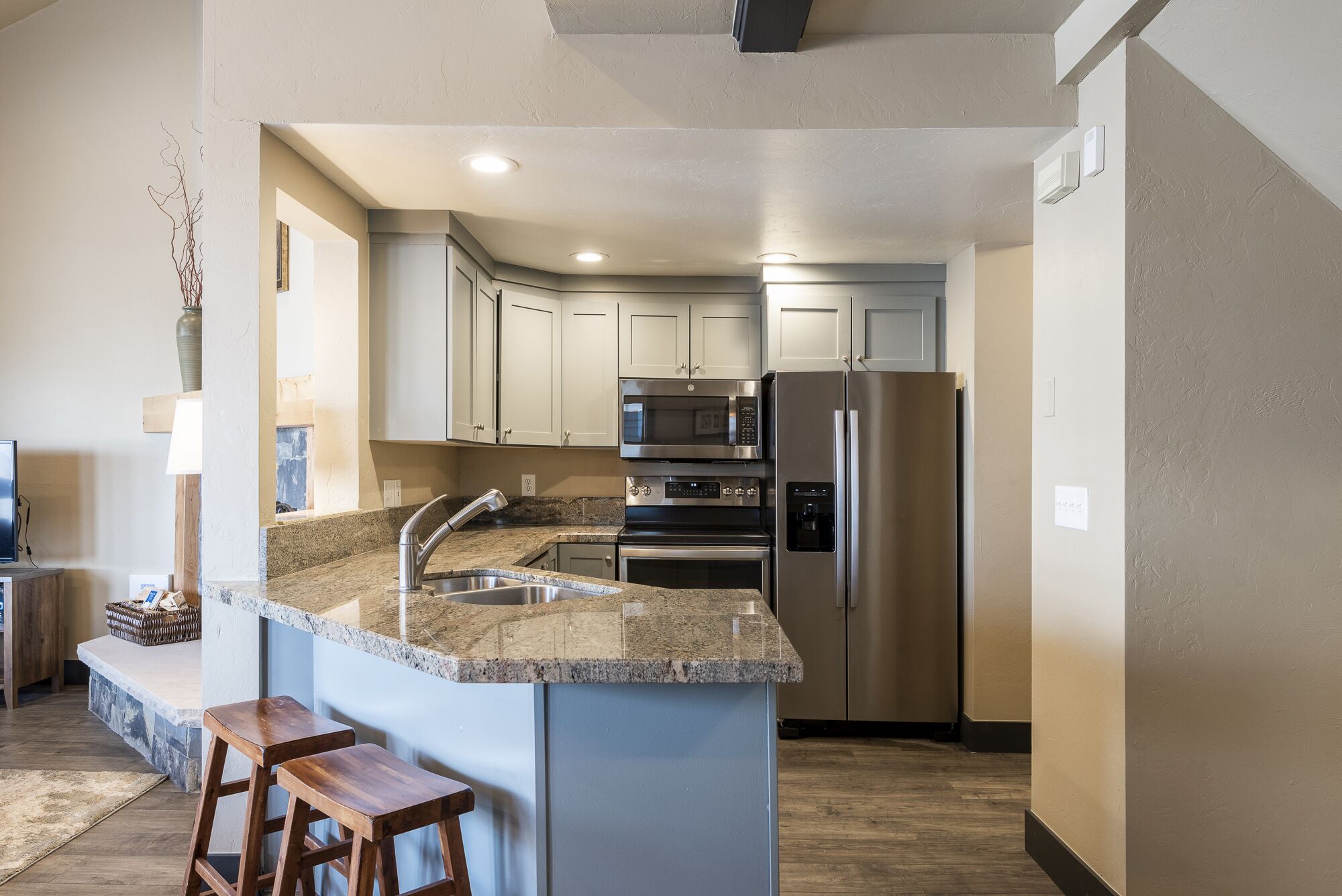 A modern kitchen with granite countertops, stainless steel appliances, and a central island with bar stools.