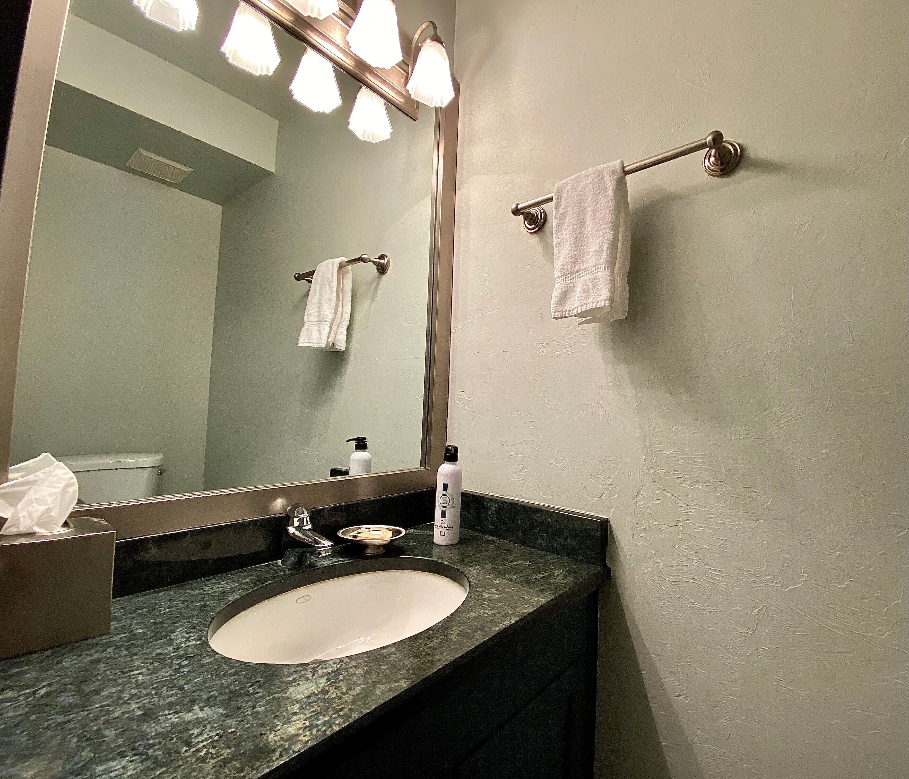 A bathroom with a sink, mirror, and towel rack.