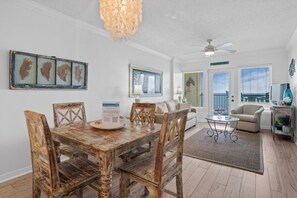 A dining area with a wooden table and chairs, a chandelier, and framed botanical prints on the wall.