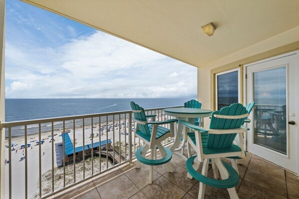 A balcony with a view of the beach and ocean.