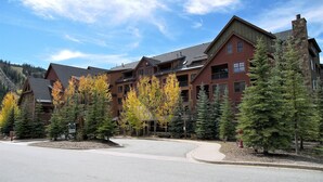 A multi-story lodge with a stone chimney, surrounded by evergreen trees and autumn-colored foliage. - River Run Village Walk To Gondola Pool Hot Tubs Restaurants and Shops DELUXE (Keystone)