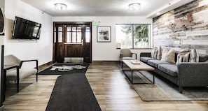 A modern living room with a wooden floor, a sofa, a coffee table, a TV, and a large window with a view of trees. - Managed by Park City Lodging-Park City Main St Location-Walk to Lift-Shuttle (PARK CITY)