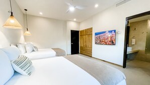 A modern hotel room with a large bed, a TV mounted on the wall, and a separate bathroom visible through an open door. - 2 BR Ocean View PH- Jacuzzi and Private Pool steps from Mamitas Beach (Playa del Carmen)