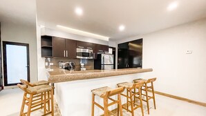 A modern kitchen with a central island and bar stools, equipped with stainless steel appliances. - 2 BR Ocean View PH- Jacuzzi and Private Pool steps from Mamitas Beach (Playa del Carmen)