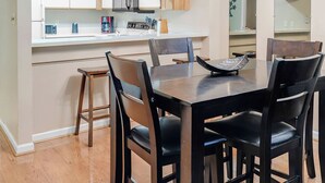 Una cocina moderna con armarios de madera, una encimera blanca y una mesa de comedor con sillas.