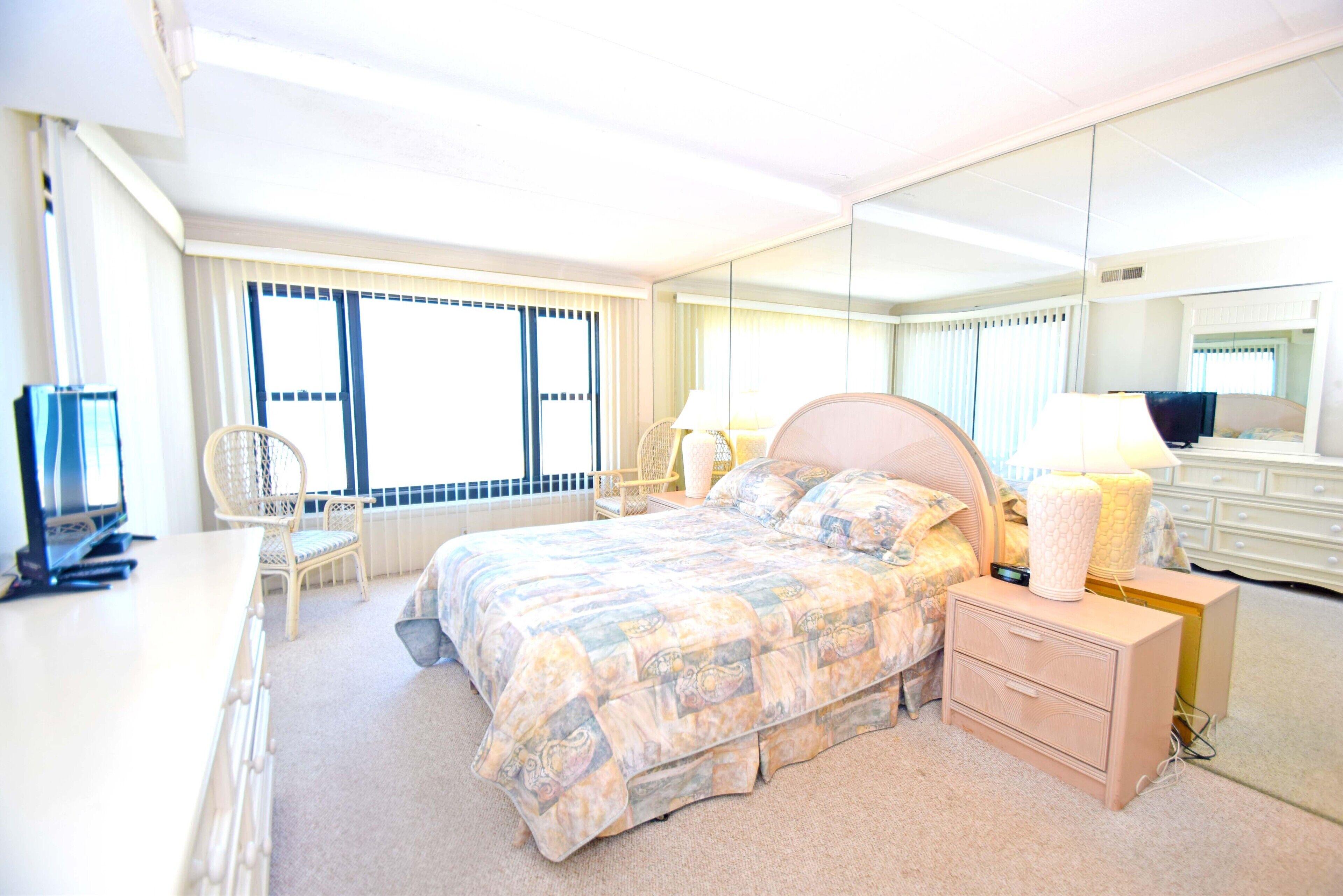 Une chambre d’hôtel comprenant un lit, une table de chevet, une lampe, une chaise et un téléviseur.
