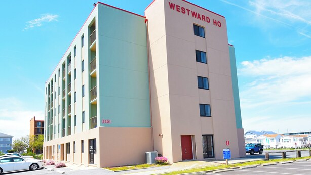 Un hotel de varios pisos con fachada color beige y azul claro, y un techo rojo, con el nombre "WESTWARD HO" en la parte superior.